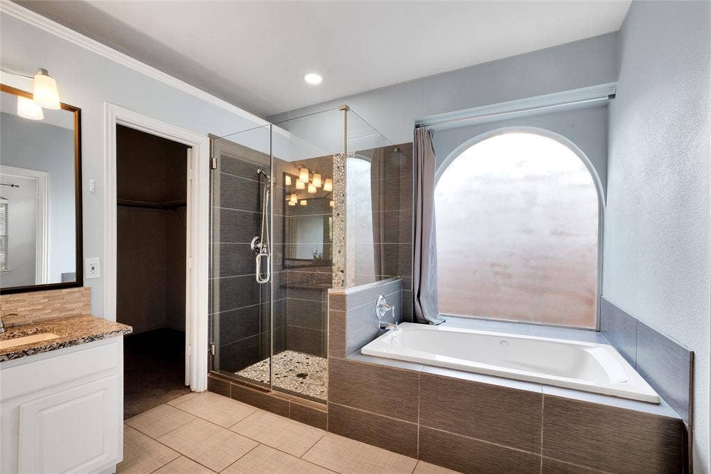 2106 Hillside Drive, Rowlett, TX 75088 Primary bath with glass shower, soaking tub, and arched window.