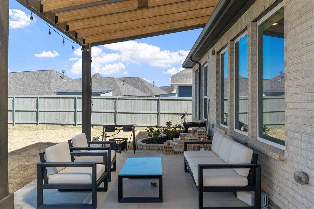 2308 Clancy Drive, Northlake, TX 76247 Covered patio with a wood-beam pergola, light-colored brick exterior, and multiple large windows