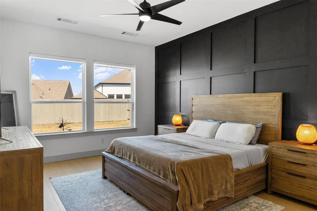 2308 Clancy Drive, Northlake, TX 76247 Light wood-finish flooring, accent wall with dark paneled millwork, black ceiling fan, and multiple windows providing natural illumination