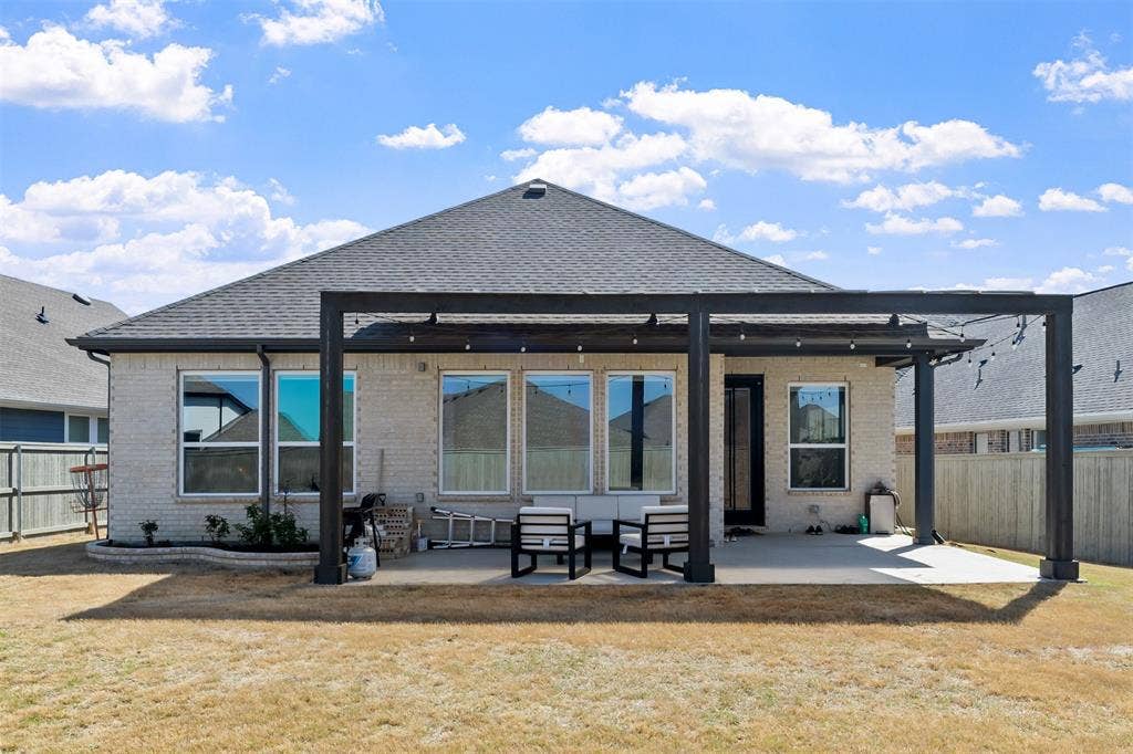 2308 Clancy Drive, Northlake, TX 76247 Expansive backyard featuring a pergola over a concrete patio, brick exterior, and multiple windows