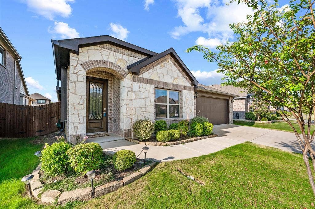 4425 Ridgehurst Lane, Fort Worth, TX 76036 Stone facade, arched entry, decorative front door, attached garage, and a landscaped front yard