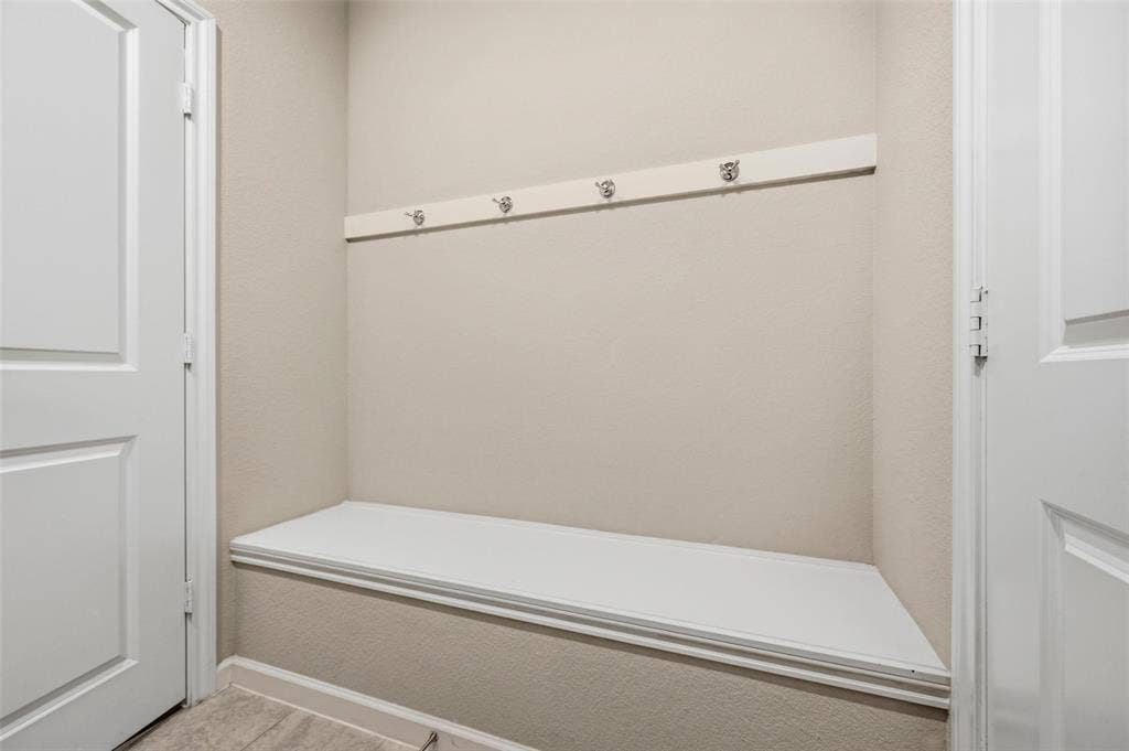 4425 Ridgehurst Lane, Fort Worth, TX 76036 Built-in bench with a white finish, featuring a wall-mounted coat rack with four hooks, and light-toned walls