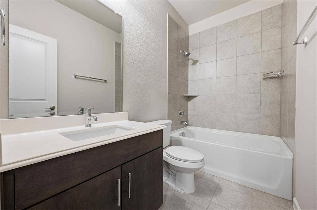 4425 Ridgehurst Lane, Fort Worth, TX 76036 Contemporary vanity with a white countertop and integrated sink, chrome fixtures, and a white bathtub with subway tile surround