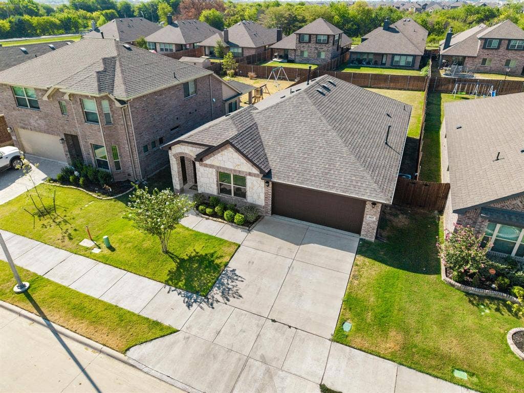 4425 Ridgehurst Lane, Fort Worth, TX 76036 Stone and brick facade with an attached two-car garage, concrete driveway, manicured lawn, and mature landscaping