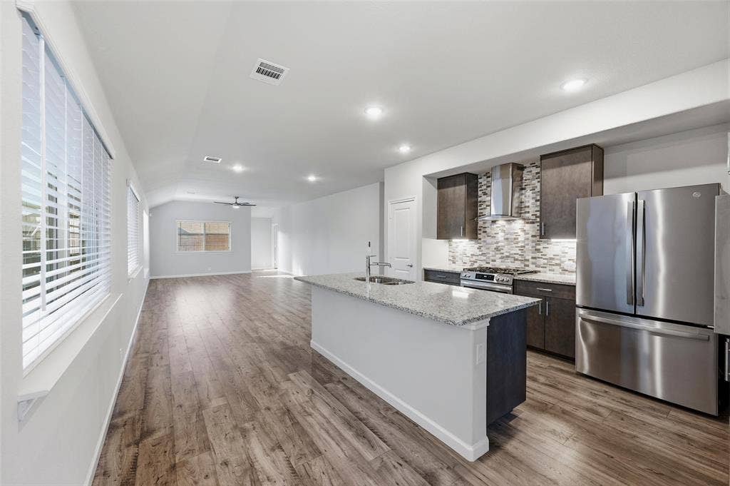 4425 Ridgehurst Lane, Fort Worth, TX 76036 Spacious kitchen featuring an island with a light-toned countertop, dark wood-finish cabinetry, stainless steel appliances, and a tiled backsplash