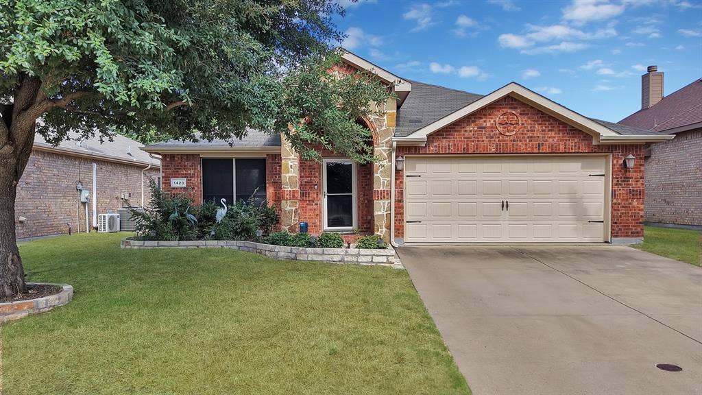 Brick and stone facade, attached garage, concrete driveway, front lawn, and mature trees