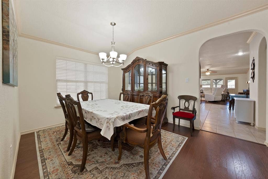 Hardwood-finish flooring, crown molding accents, and a window with blinds