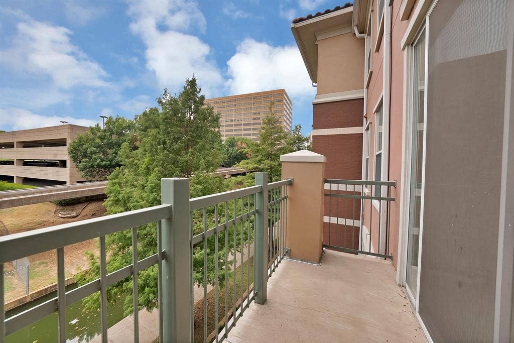 330 Las Colinas Boulevard E, #338, Irving, TX 75039 Balcony with a metal railing and stucco pillar, complemented by a sliding glass door