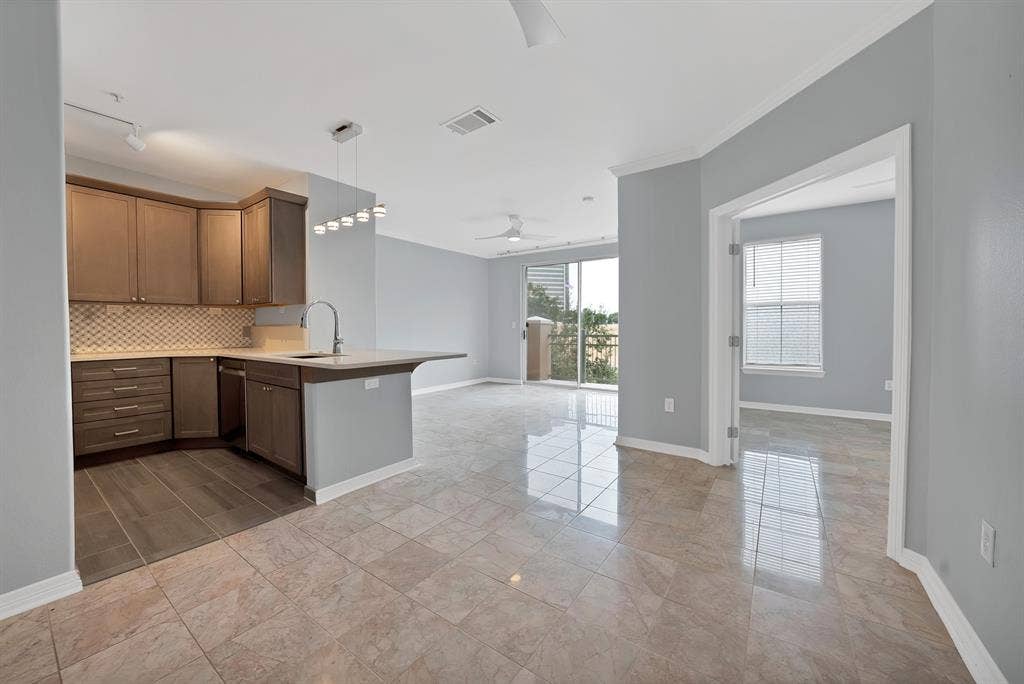 330 Las Colinas Boulevard E, #338, Irving, TX 75039 Kitchen with wood-finish cabinetry, tile backsplash, and a breakfast bar