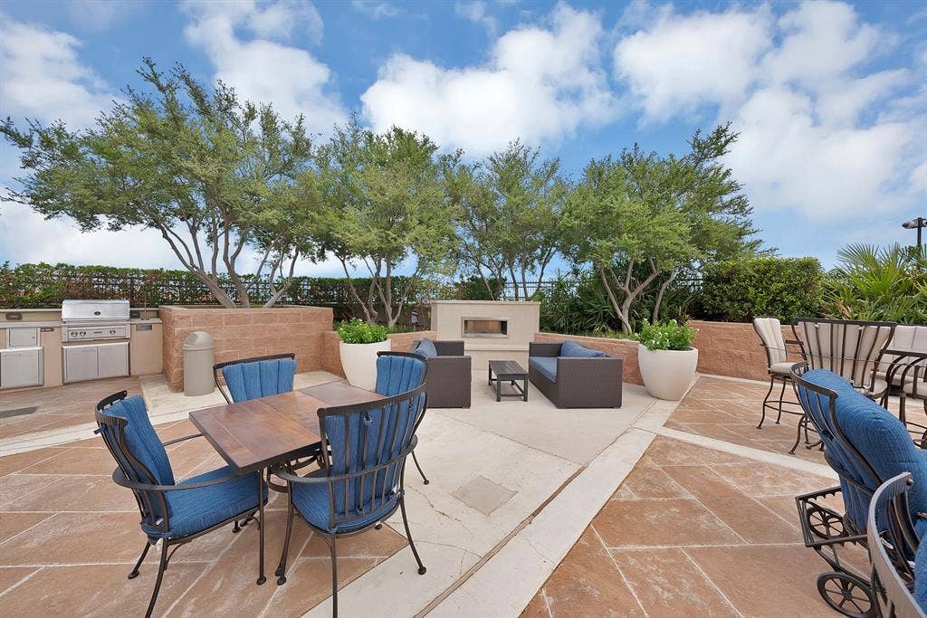 330 Las Colinas Boulevard E, #338, Irving, TX 75039 Expansive outdoor patio with stone paving, built-in outdoor kitchen, integrated fireplace, and mature trees