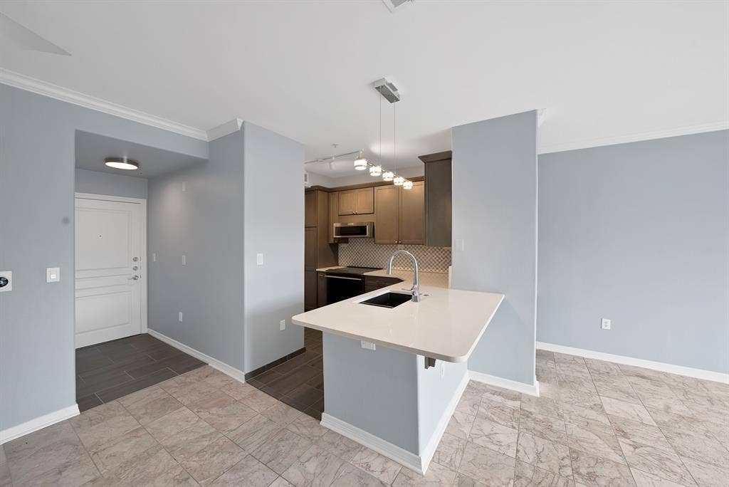 330 Las Colinas Boulevard E, #338, Irving, TX 75039 Kitchen island with a light-toned countertop, stainless steel sink, and modern pendant lighting