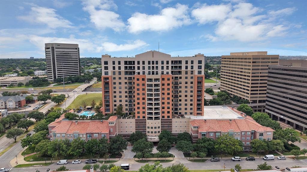 330 Las Colinas Boulevard E, #338, Irving, TX 75039 Multi-story building featuring balconies, a ground-level pool, and mature trees surrounding the entrance