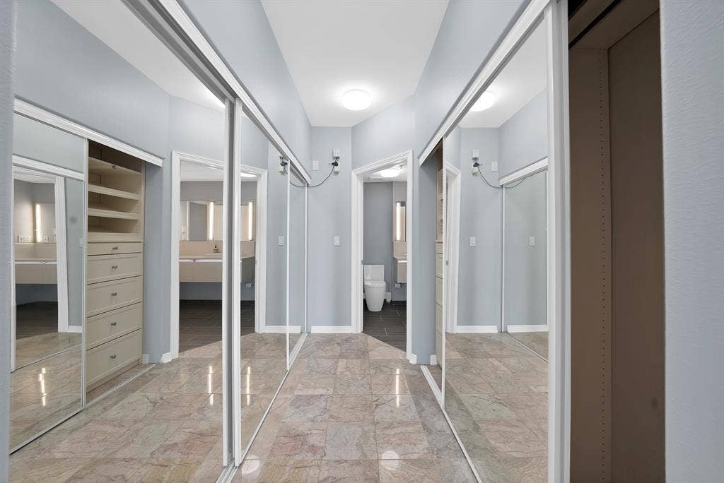 330 Las Colinas Boulevard E, #338, Irving, TX 75039 Mirrored sliding closet doors, built-in closet organization with drawers and shelving, recessed lighting, and stone flooring