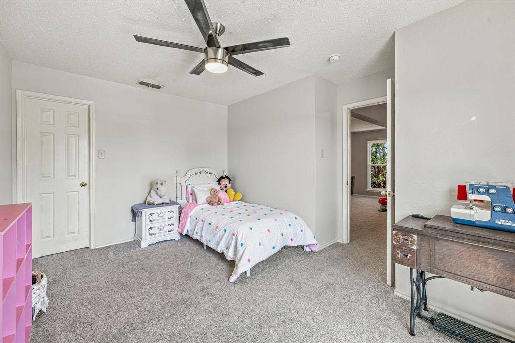 6913 Chaco Trail, Fort Worth, TX 76137 Neutral gray carpeting and walls, white paneled door, and a ceiling fan with integrated lighting