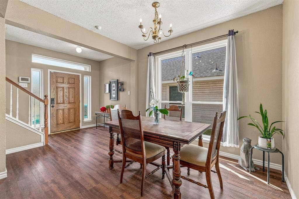 6913 Chaco Trail, Fort Worth, TX 76137 Wood-finish flooring throughout, solid wood front door with sidelights and transom window, traditional chandelier, and large window with vertical blinds