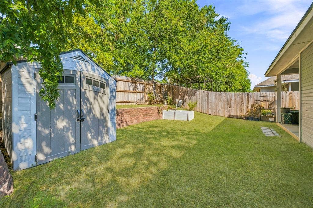 6913 Chaco Trail, Fort Worth, TX 76137 Expansive backyard featuring a manicured lawn, wood privacy fencing, and a permanent storage shed