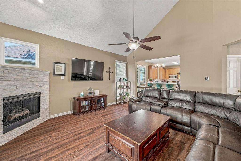 6913 Chaco Trail, Fort Worth, TX 76137 Vaulted ceiling, wood-finish flooring, stone-clad fireplace, ceiling fan, and open concept design