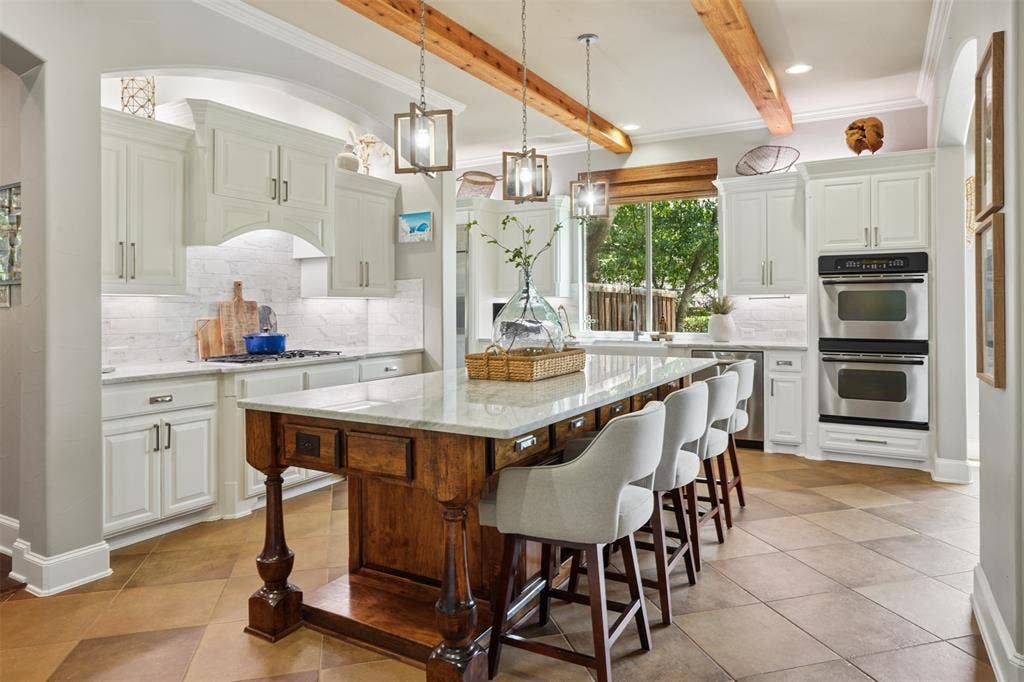 1712 Singletree Court, McKinney, TX 75072 Custom carved island anchors the remodeled kitchen beneath warm rough-finish pine ceiling beams.