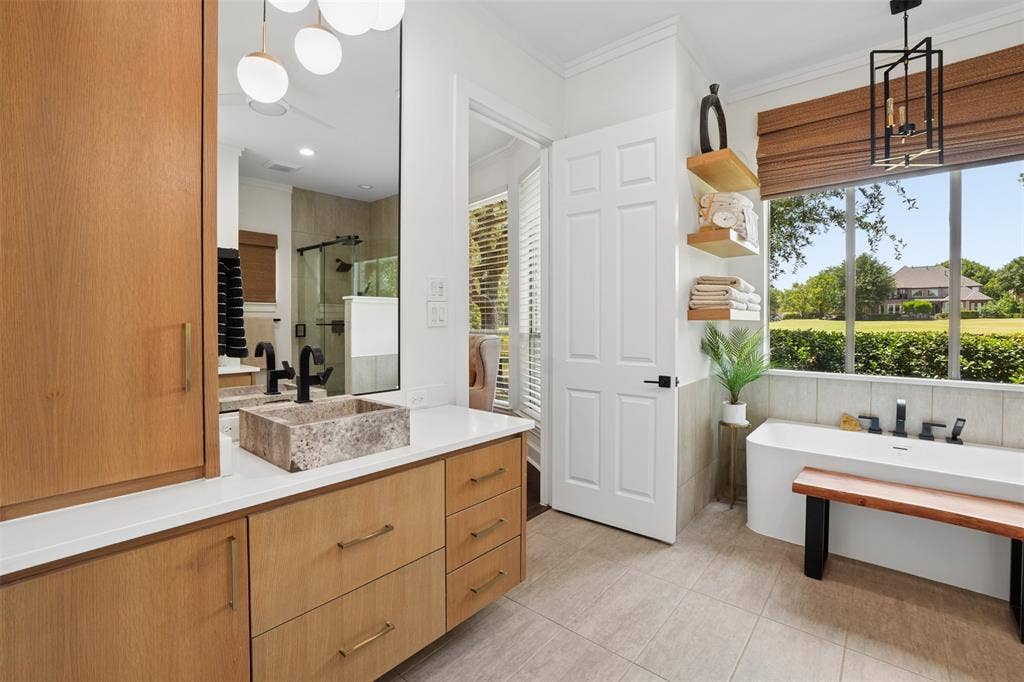 1712 Singletree Court, McKinney, TX 75072 Spacious primary bathroom combines warm wood cabinetry with light, timeless finishes.