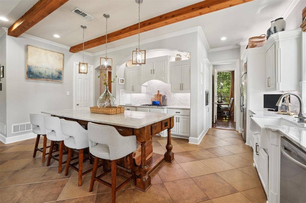1712 Singletree Court, McKinney, TX 75072 Remodeled kitchen combines marble countertops, custom wood details and an island with a breakfast bar for gathering.