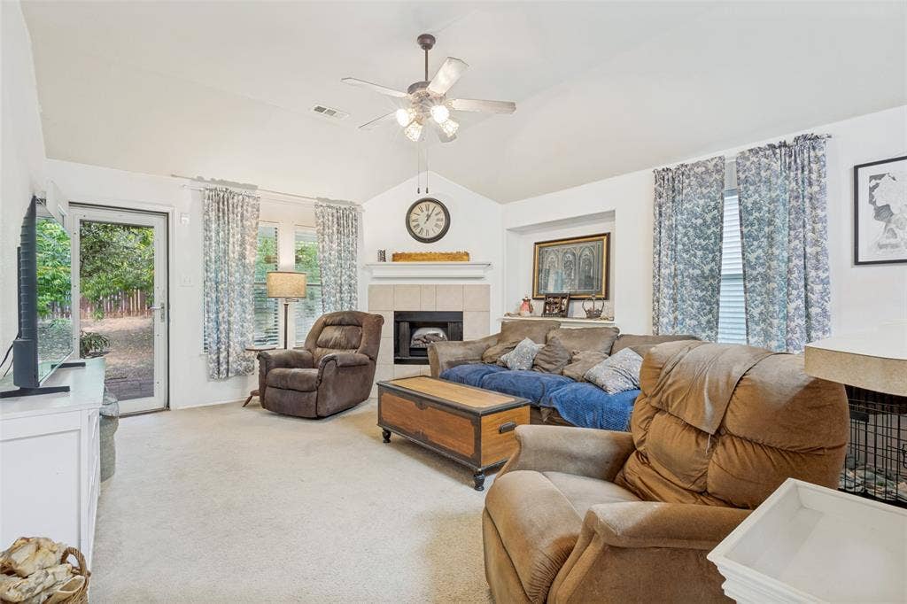2118 Hanakoa Falls Drive, Anna, TX 75409 Vaulted ceiling living area featuring a wood buring fireplace with a mantel, ceiling fan, and carpeted flooring