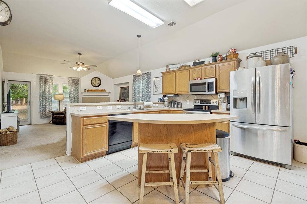 2118 Hanakoa Falls Drive, Anna, TX 75409 Kitchen featuring tile flooring, wood-finish cabinetry, stainless steel appliances, and a breakfast bar