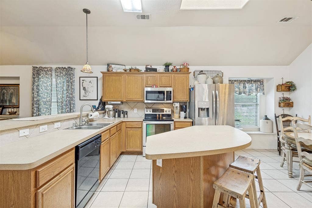 2118 Hanakoa Falls Drive, Anna, TX 75409 Kitchen featuring wood cabinetry, stainless steel appliances, a center island, and white tile flooring
