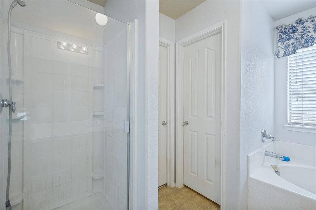 2118 Hanakoa Falls Drive, Anna, TX 75409 Shower enclosure with clear glass door, tile surround, and built-in shelving