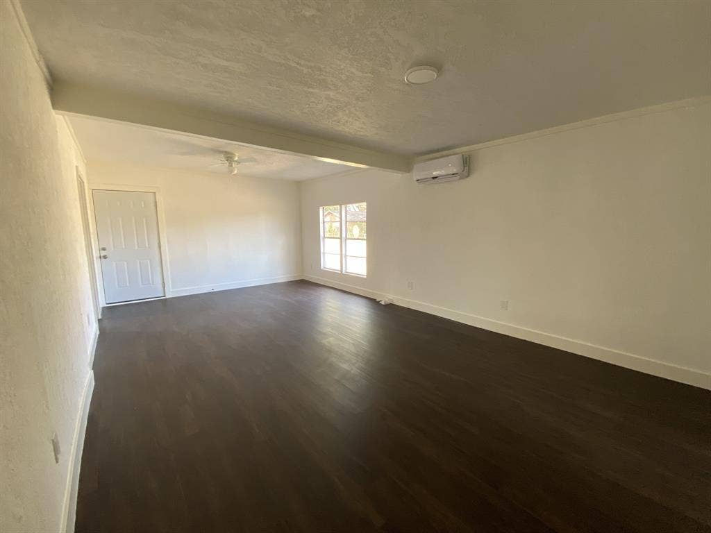 801 Walnut Street, Trinidad, TX 75163 Dark wood-finish flooring, white walls, ceiling-mounted light fixture, split air conditioning unit, and multi-pane window