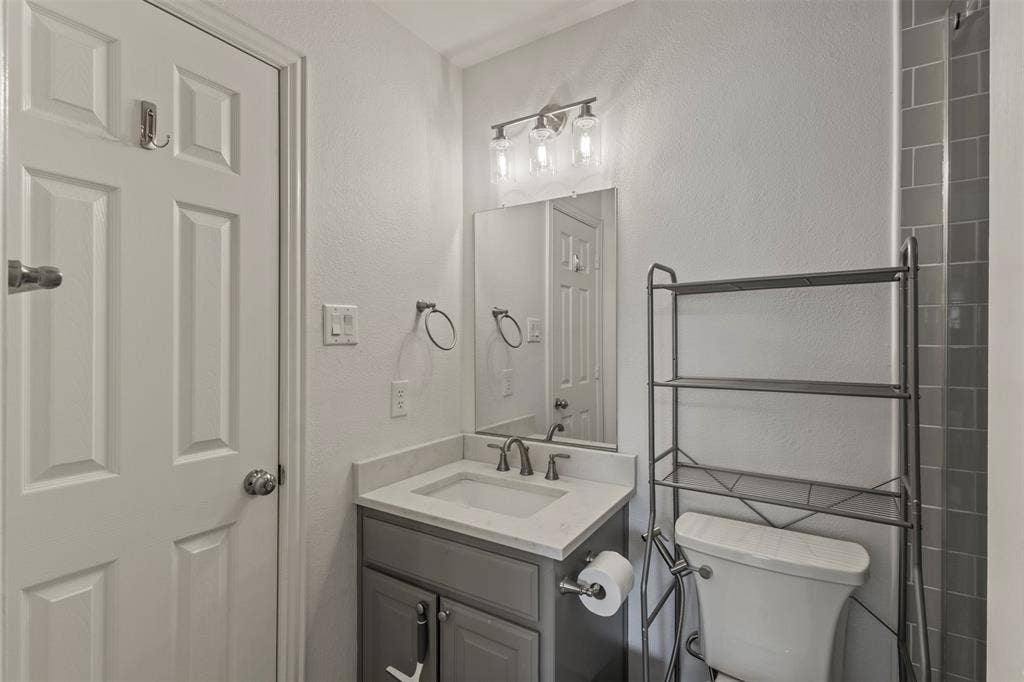 Vanity with integrated sink and chrome faucet, rectangular mirror, and three-light vanity bar