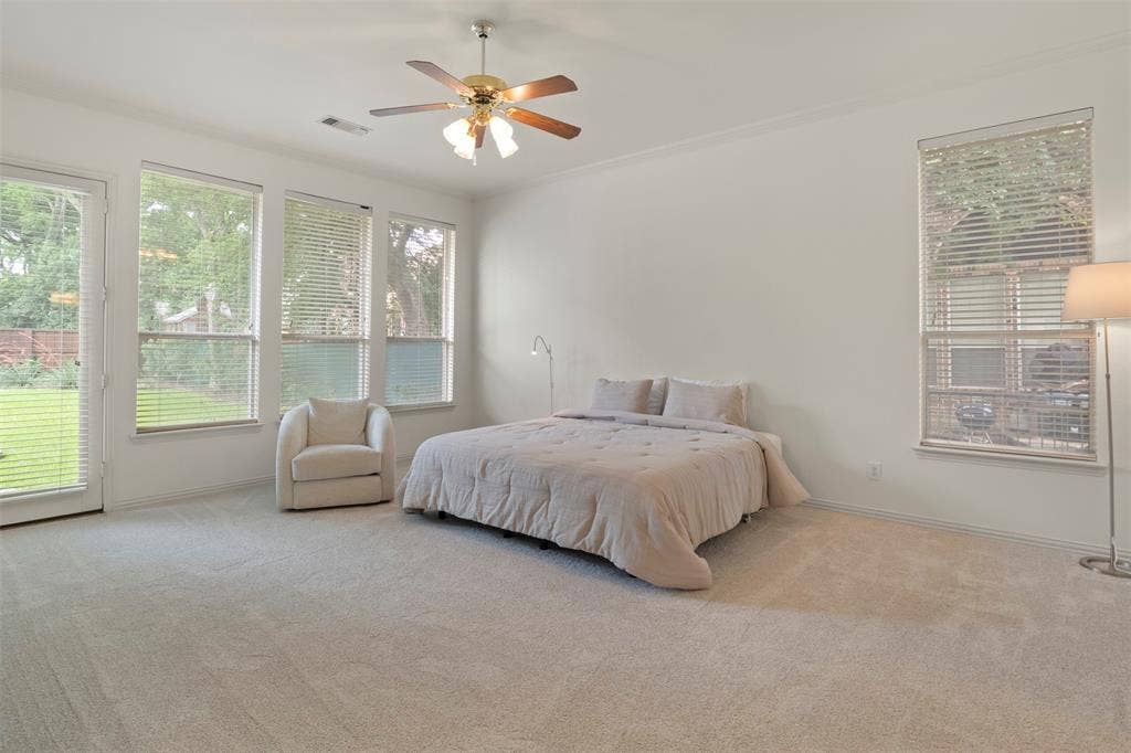 Carpeted flooring, vaulted ceiling with a ceiling fan, multiple windows with blinds, and a glass-paneled door