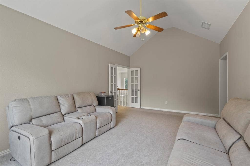 Vaulted ceiling with a ceiling fan, neutral wall paint, and carpet flooring