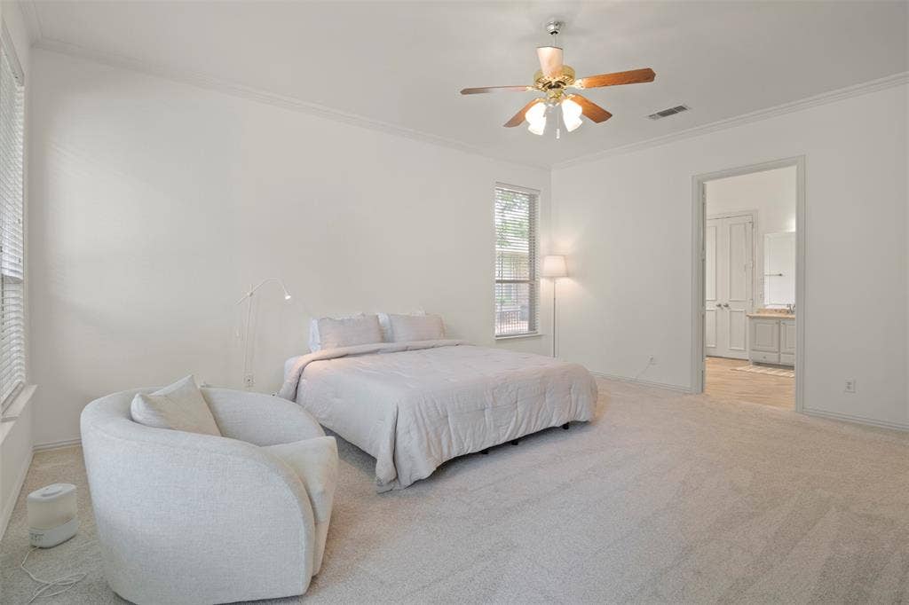 Spacious room featuring neutral carpeting, a ceiling fan, crown molding, and a window with blinds