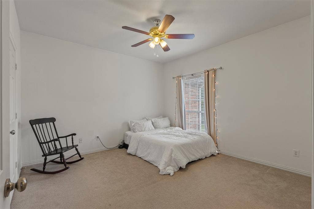Carpeted room featuring a ceiling fan with integrated lighting, a window with blinds, and white walls