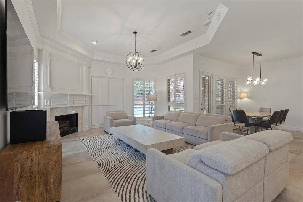 Recessed lighting, tray ceiling, fireplace with stone surround, wood-finish flooring, and plantation shutters