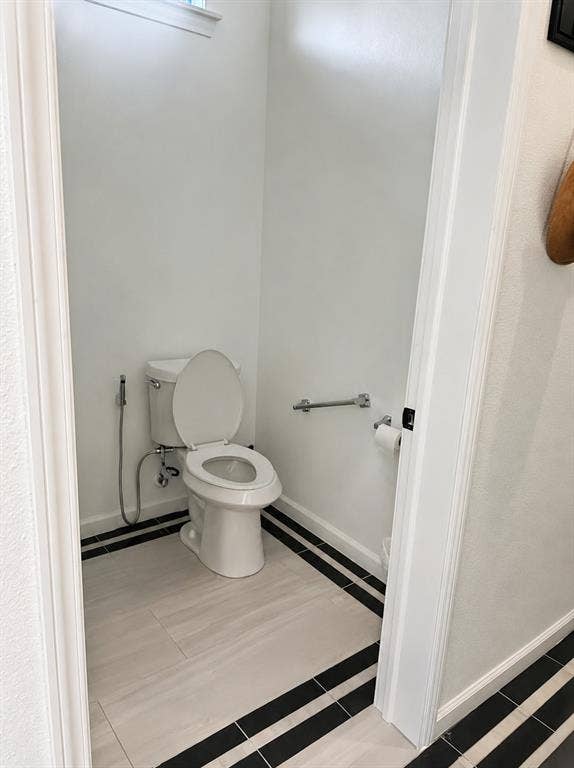 703 E Oates Road, Garland, TX 75043 White toilet with an attached bidet sprayer