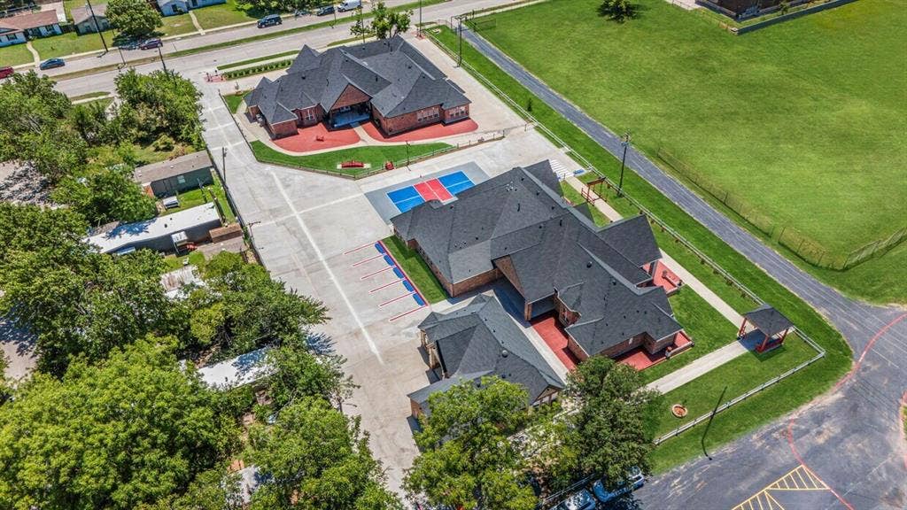 703 E Oates Road, Garland, TX 75043 Expansive paved parking area, two brick structures with dark shingle roofs, dedicated athletic court, and a gazebo on a manicured lawn