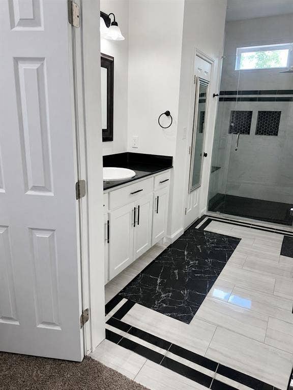 703 E Oates Road, Garland, TX 75043 White shaker-style cabinetry with matte black hardware, dark stone countertop, vessel sink, and a walk-in shower with a glass enclosure