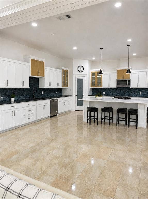 703 E Oates Road, Garland, TX 75043 White cabinetry with gold-toned glass-front accents, dark tile backsplash, and light-toned tile flooring