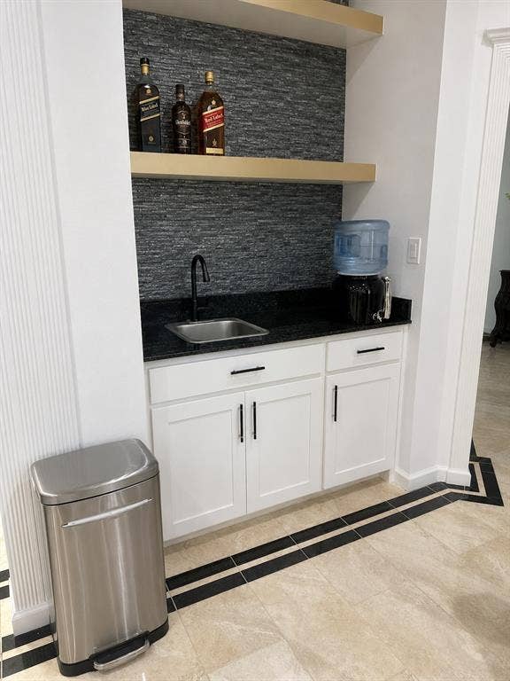 703 E Oates Road, Garland, TX 75043 Built-in wet bar with white cabinetry, dark countertop, and stone-finish backsplash