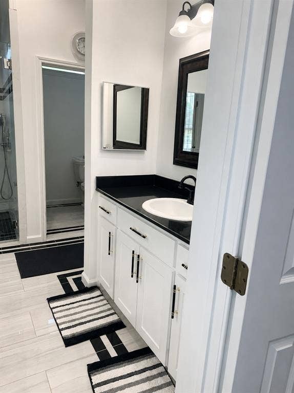703 E Oates Road, Garland, TX 75043 White vanity with black hardware, black countertop, and undermount sink