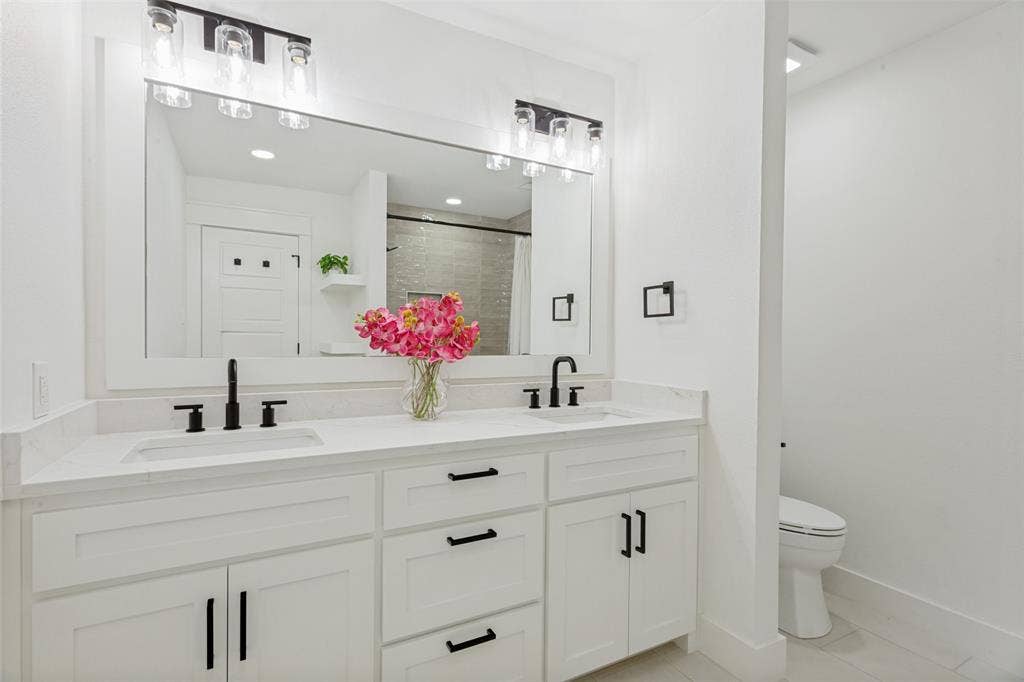 4316 Springbranch Drive, Benbrook, TX 76116 Dual vanity with stone-finish countertop, matte black fixtures, and framed mirror
