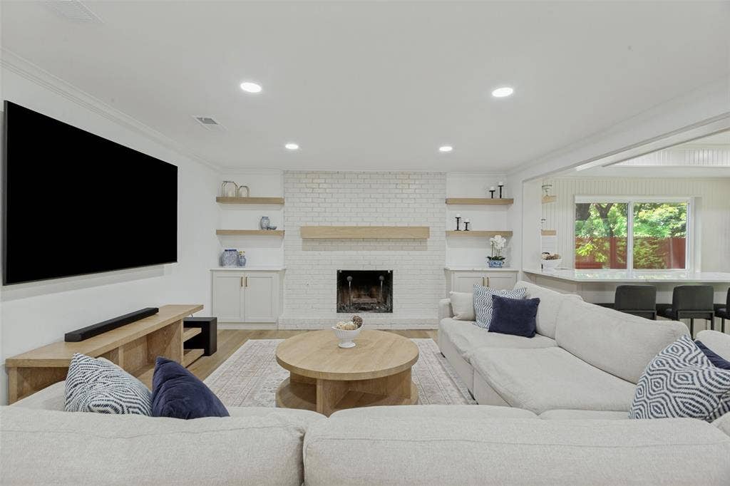 4316 Springbranch Drive, Benbrook, TX 76116 White brick fireplace with a wood mantle and hearth, flanked by built-in cabinetry and floating wood shelves