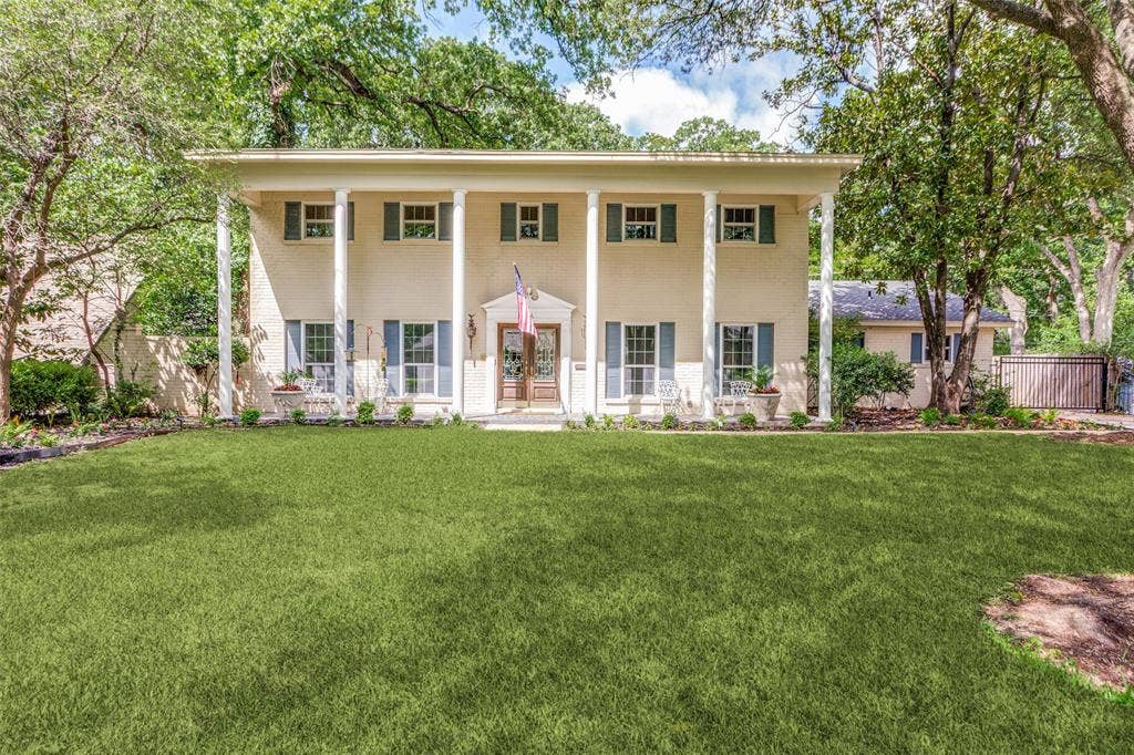 4316 Springbranch Drive, Benbrook, TX 76116 Two-story Colonial-style exterior, full-width covered porch with white columns, light-colored brick facade, dark-toned window shutters, and a prominent front lawn