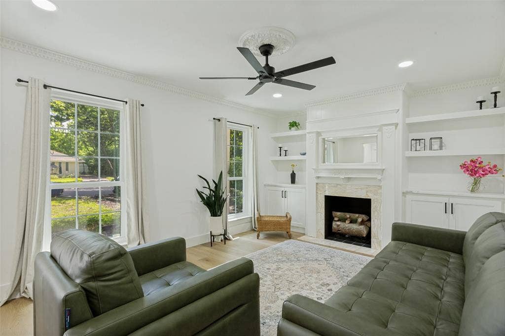 4316 Springbranch Drive, Benbrook, TX 76116 Living area featuring light wood-finish flooring, a ceiling fan with decorative medallion, a fireplace with stone surround, and built-in shelving and cabinetry