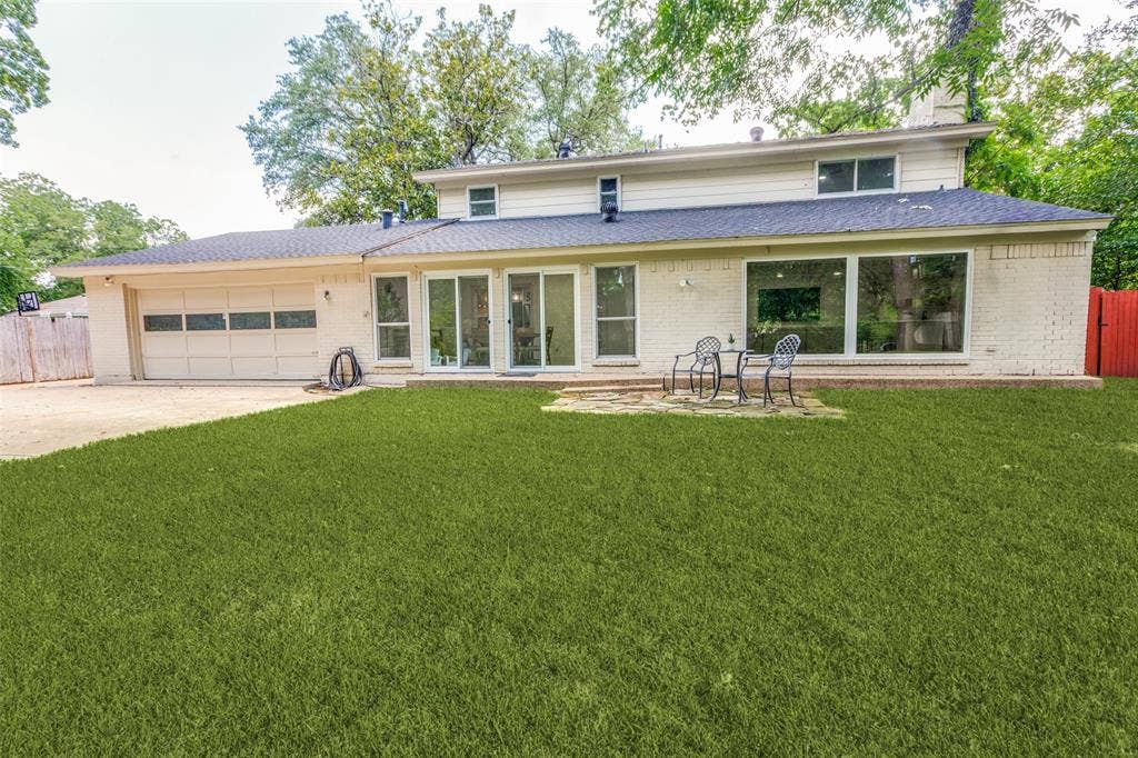 4316 Springbranch Drive, Benbrook, TX 76116 Expansive lawn, patio area, large sliding glass doors, multiple oversized windows, and an attached garage