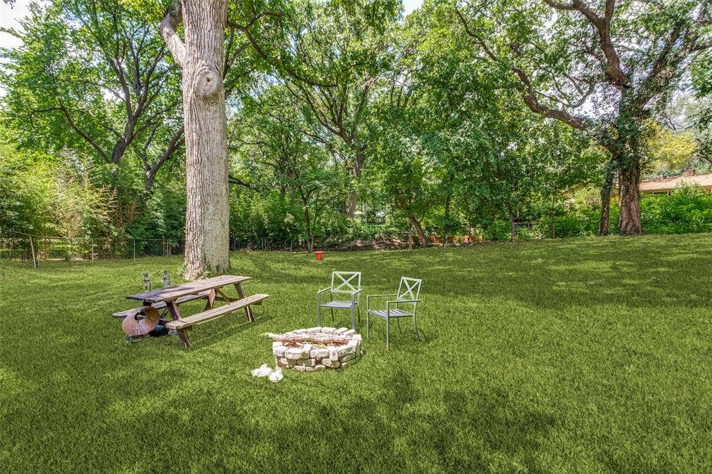 4316 Springbranch Drive, Benbrook, TX 76116 Expansive green lawn with mature trees, a stone-lined fire pit, and a picnic table