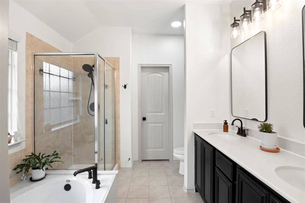 2189 Liriope Lane, Waxahachie, TX 75165 primary bath with dual sinks, separate soaking tub and separate shower. Updated black fixtures and mirrors give the space a clean, current look.