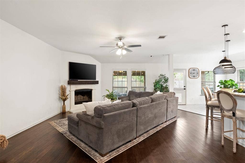 2189 Liriope Lane, Waxahachie, TX 75165 A closer view of the WOOD-BURNING FIREPLACE and the wall of windows overlooking the backyard and extended covered porch—bringing natural light into the heart of the home.