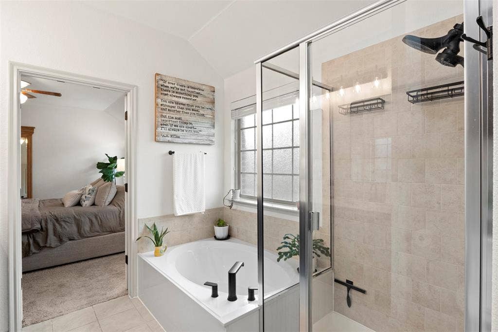 2189 Liriope Lane, Waxahachie, TX 75165 No need to choose between a tub and shower—the primary bath includes both a separate soaking tub and enclosed shower, with updated black plumbing fixtures adding a modern finish.